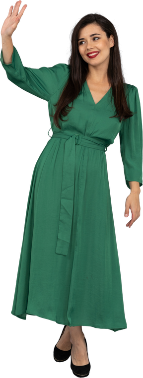 Вид спереди приветствующей молодой леди в зеленом платье