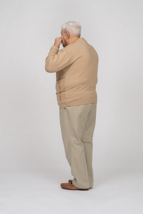 Side view of an old man in casual clothes touching face