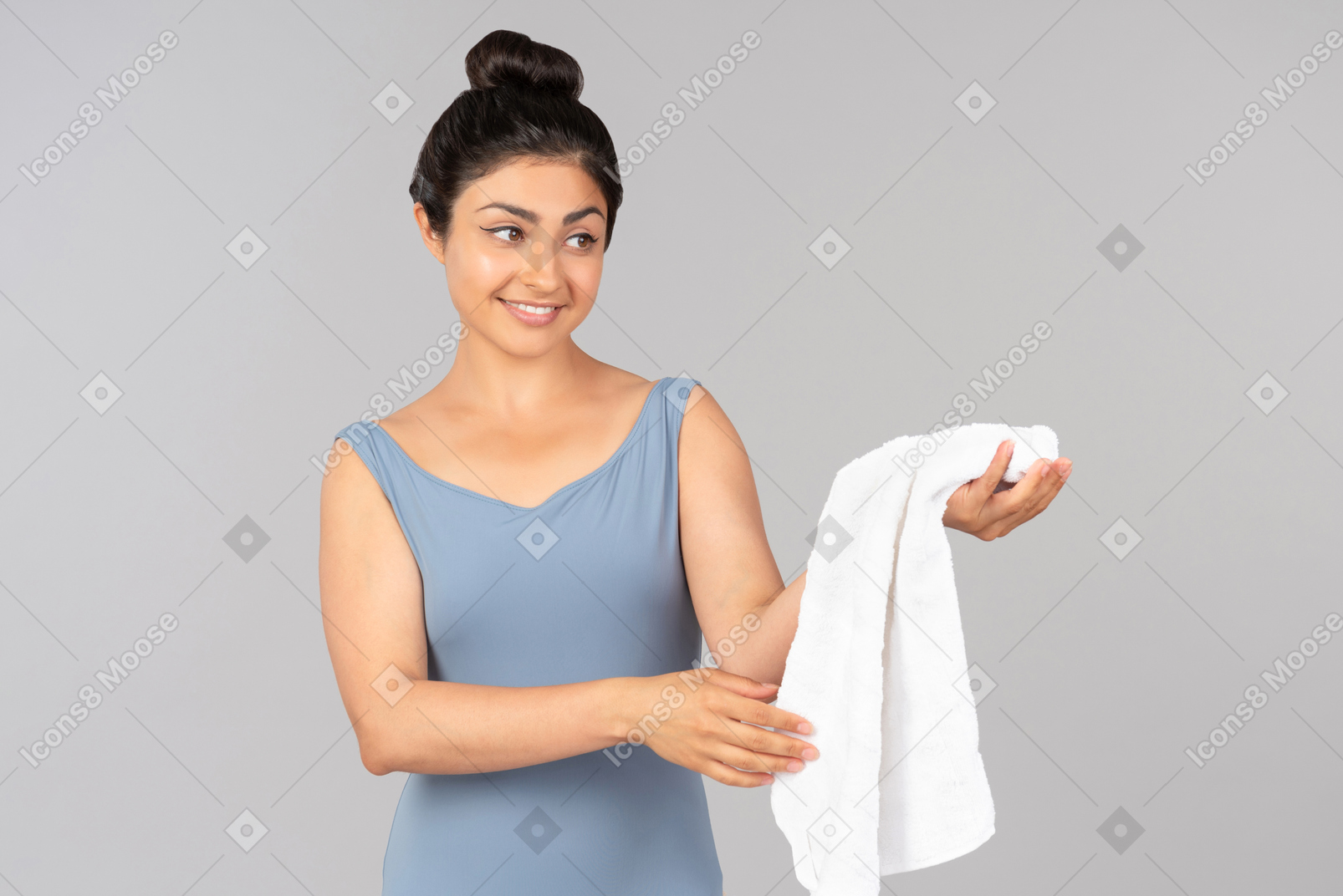 Улыбающаяся молодая индийская женщина, держащая белое полотенце