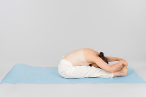 Jeune femme indienne assise sur un tapis de yoga plié