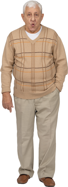 Front view of an old man in casual clothes standing with hand in pocket and looking at camera