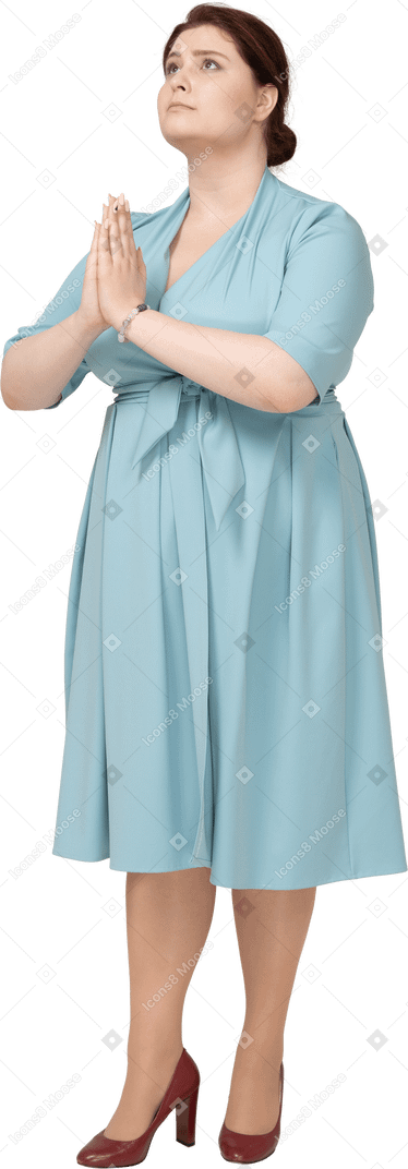 Vue de face d'une femme en robe bleue faisant un geste de prière