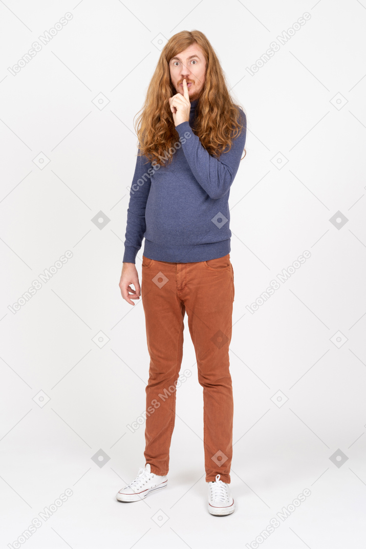 Vista frontal de um jovem em roupas casuais, mostrando sinal de silêncio