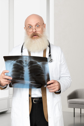 A man in a white lab coat holding a x - ray