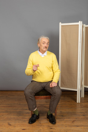 Middle-aged man sitting on chair and looking at camera