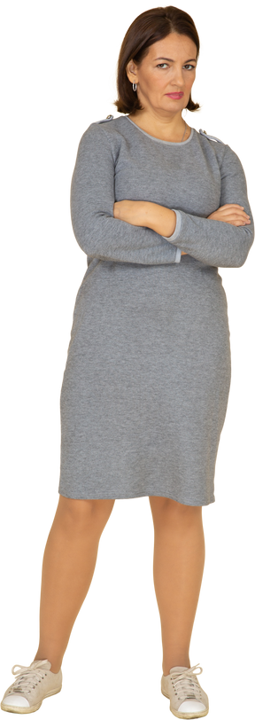 Vue de face d'une femme en robe grise posant avec les bras croisés