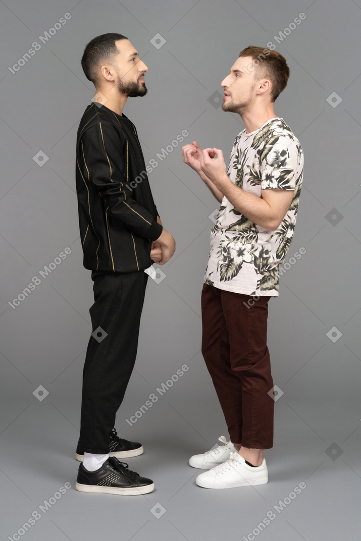 何かについて話し合っている2人の若い男性の側面図