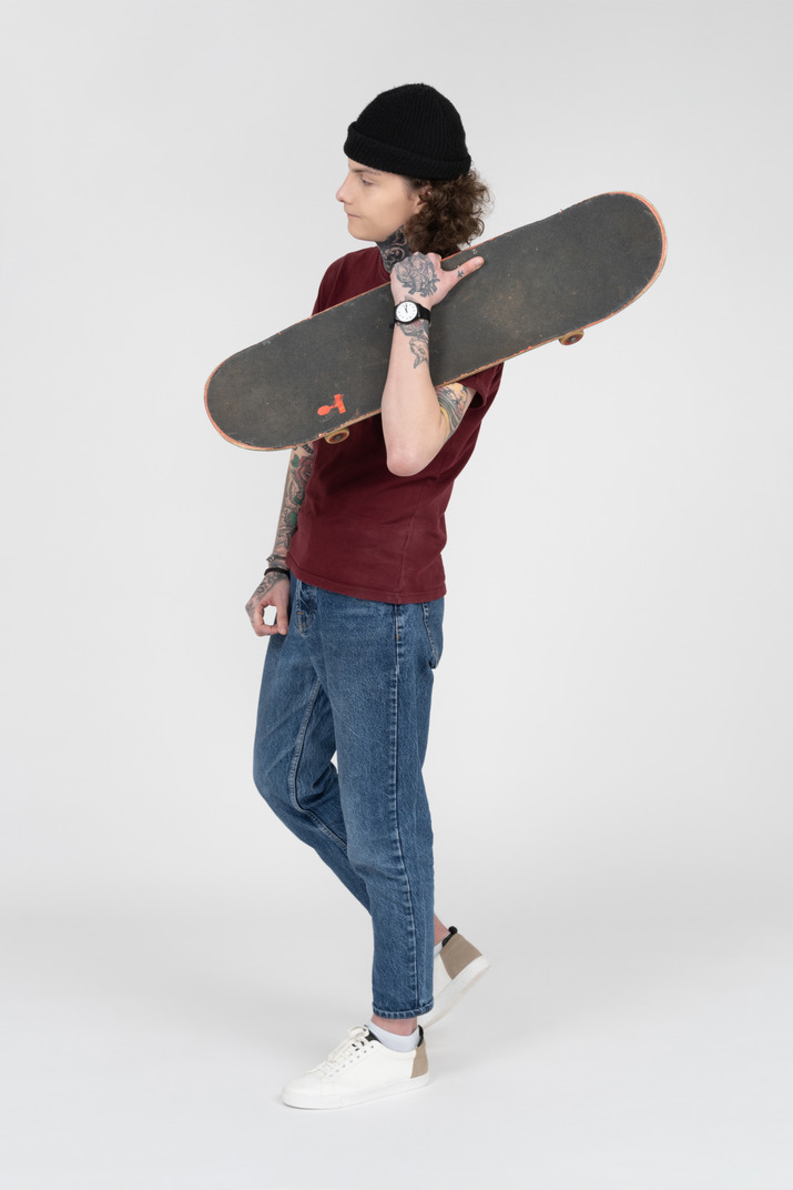 A teenager walking with his skateboard