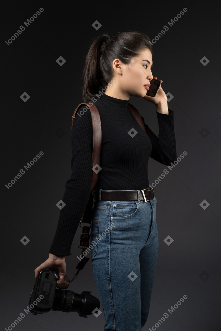 Mujer joven con cámara hablando por teléfono