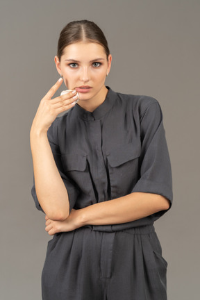 Front view of a young woman in a jumpsuit removing make-up