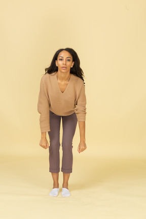 Vista frontal de una mujer joven de piel oscura levantando pesas