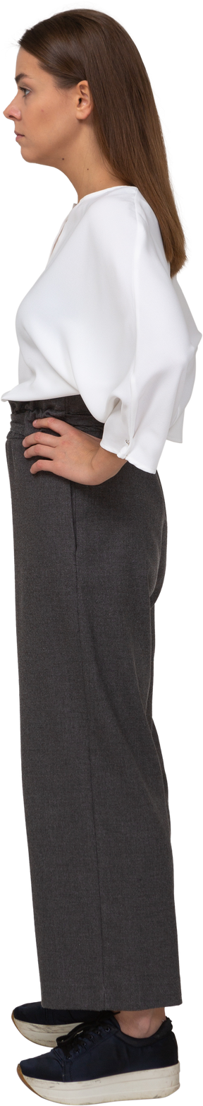 Side view of a serious young lady in office clothing putting hands on hips