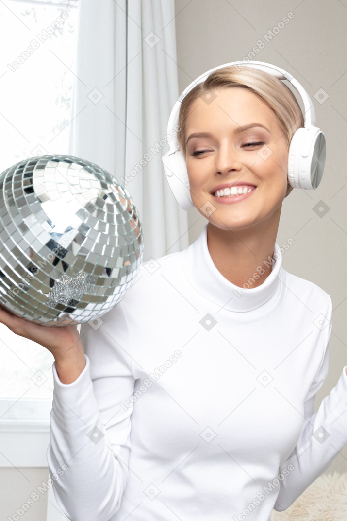 A woman wearing headphones holding a disco ball