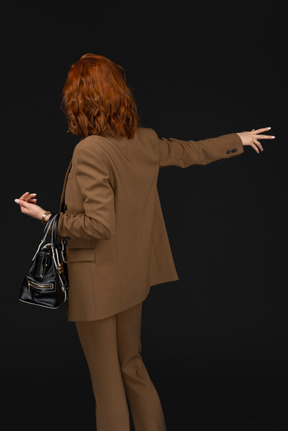 Back view of a woman in a brown suit hailing a cab