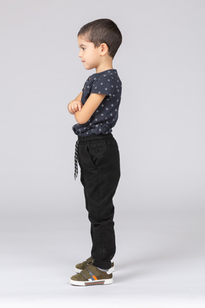 Side view of a cute boy standing with crossed arms