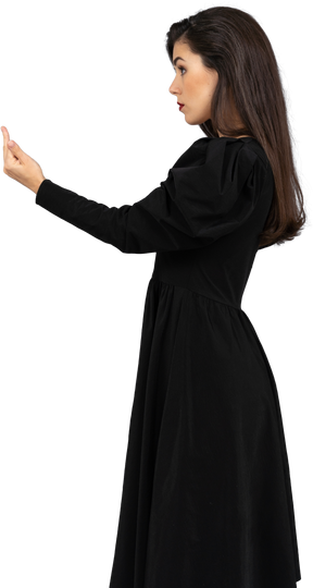 Vista lateral de uma jovem de vestido preto mostrando o dedo médio