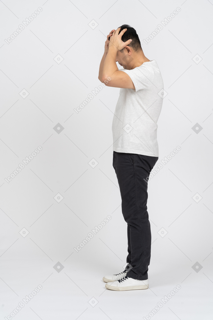 Seitenansicht eines mannes in freizeitkleidung, der mit den händen auf dem kopf steht