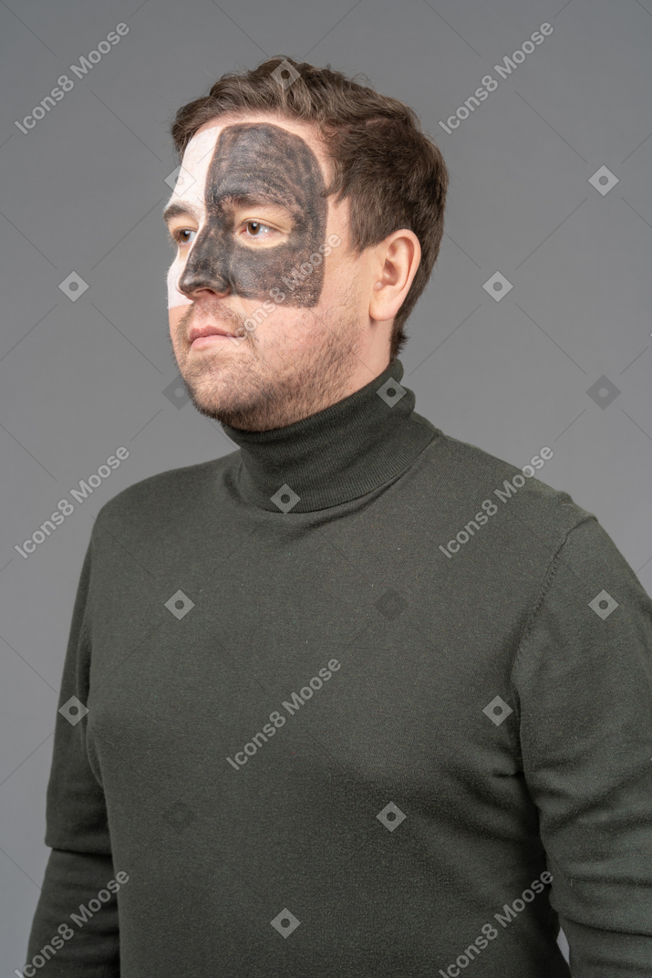 Three-quarter view of a male football fan with a black & white face art