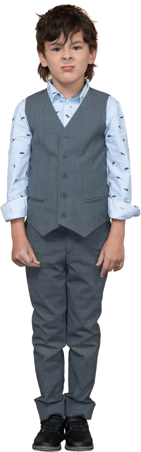 Front view of a cute boy in grey suit making faces and looking at camera