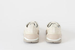 A back shot of a pair of white and beige sneakers