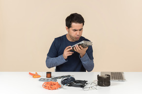 A young man in casual blue clothes working with computer details