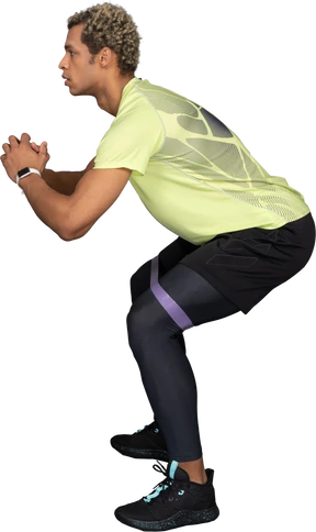 Side view of a dark-skinned young man squatting with an elastic rubber