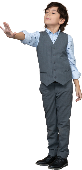 Front view of a boy in grey suit showing stop gesture