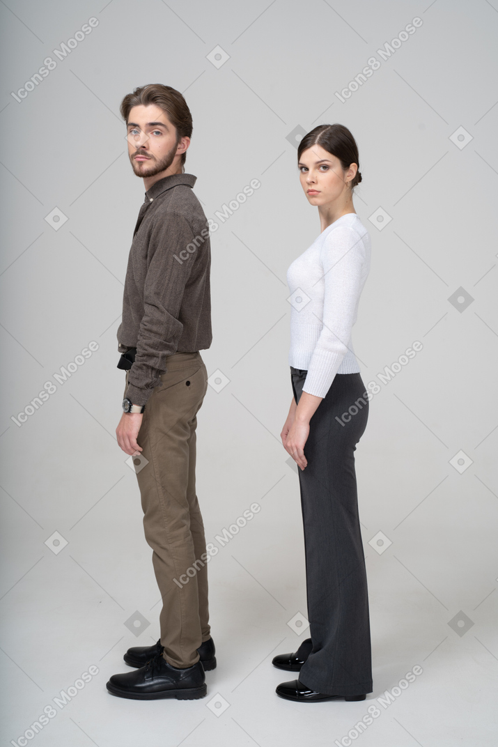Vista laterale di una giovane coppia in abiti da ufficio girando la testa