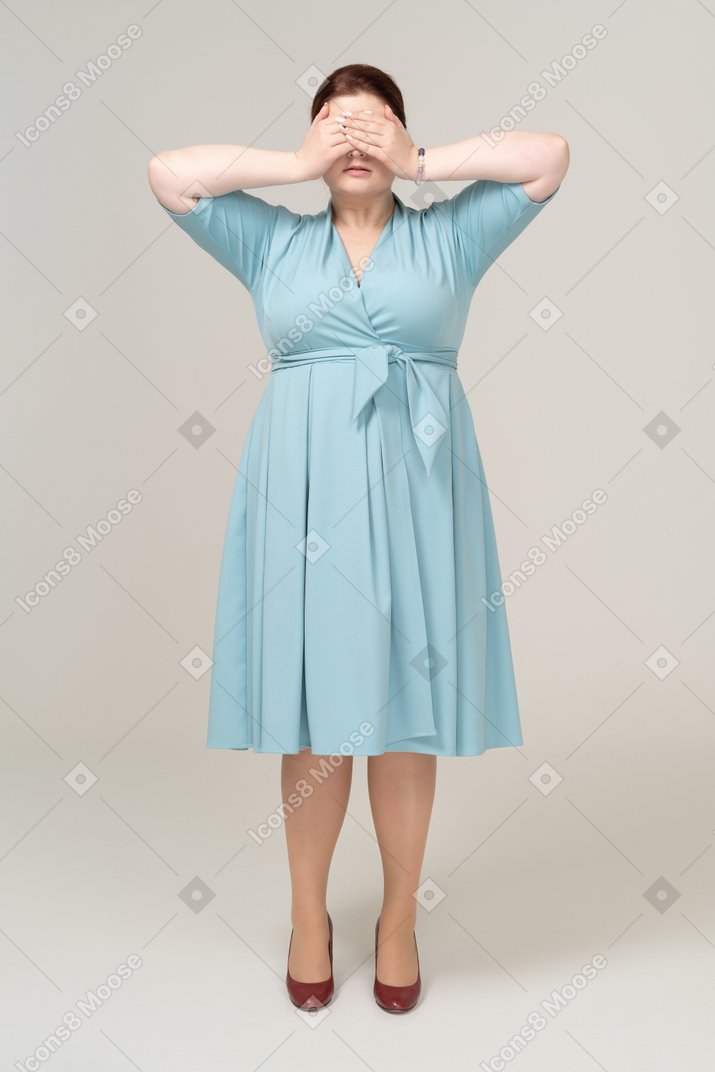 Vista frontale di una donna in abito blu che chiude gli occhi con le mani