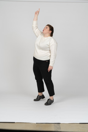 Front view of a plus size woman in casual clothes standing with raised arm