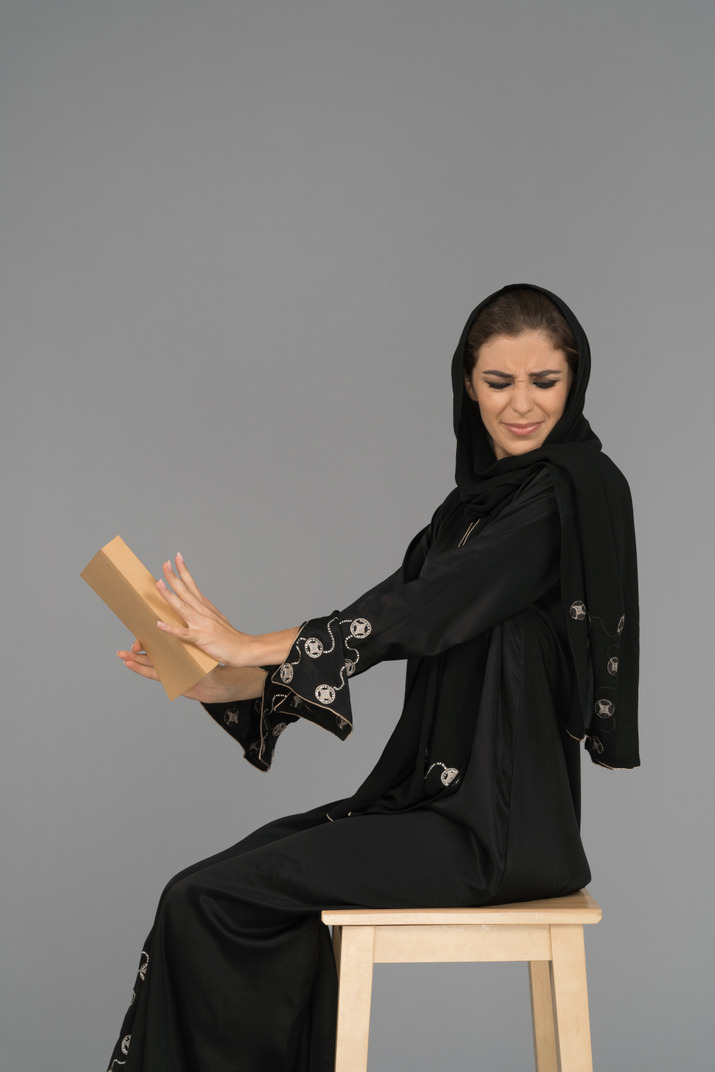 Young arab woman rejecting to read a book