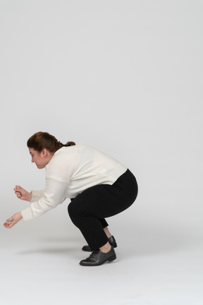 Vista laterale di una donna grassoccia in abiti casual accovacciata