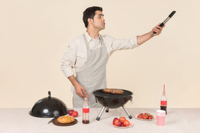 Joven hombre caucásico gritando algo mientras prepara barbacoa