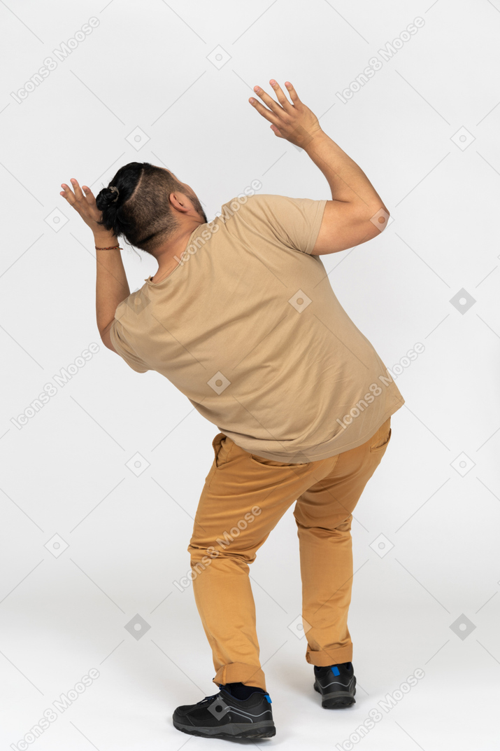 Scared asian man raising hands and looking up