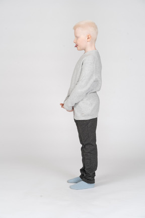 Vista lateral de um garoto garoto em roupas casuais, mostrando a língua