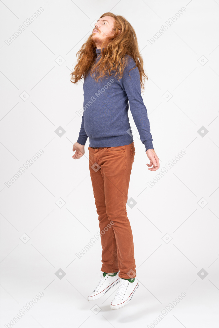 カジュアルな服を着てジャンプする若い男の側面図