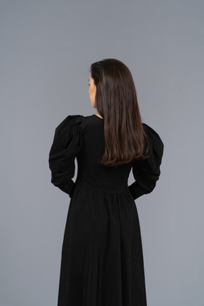 Vista posteriore di una giovane donna in un abito nero che tengono le mani insieme