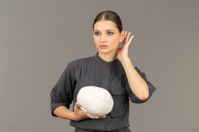 Front view of a young woman in a jumpsuit holding a plaster skull