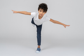 Um menino de pé em uma perna e equilibrando com as mãos