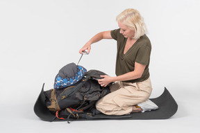 Mature female tourist organising tourist backpack