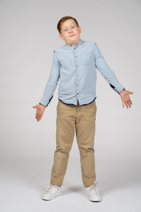 Front view of a confused boy standing with outstretched arms