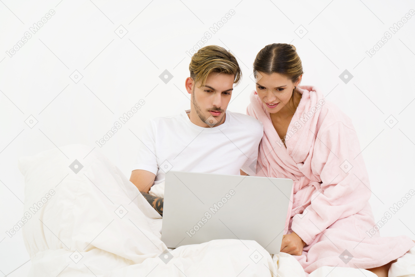 Couple assis dans son lit et regardant un ordinateur portable