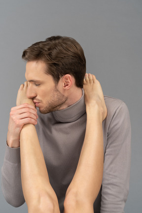 A pleased young man kissing a female`s foot