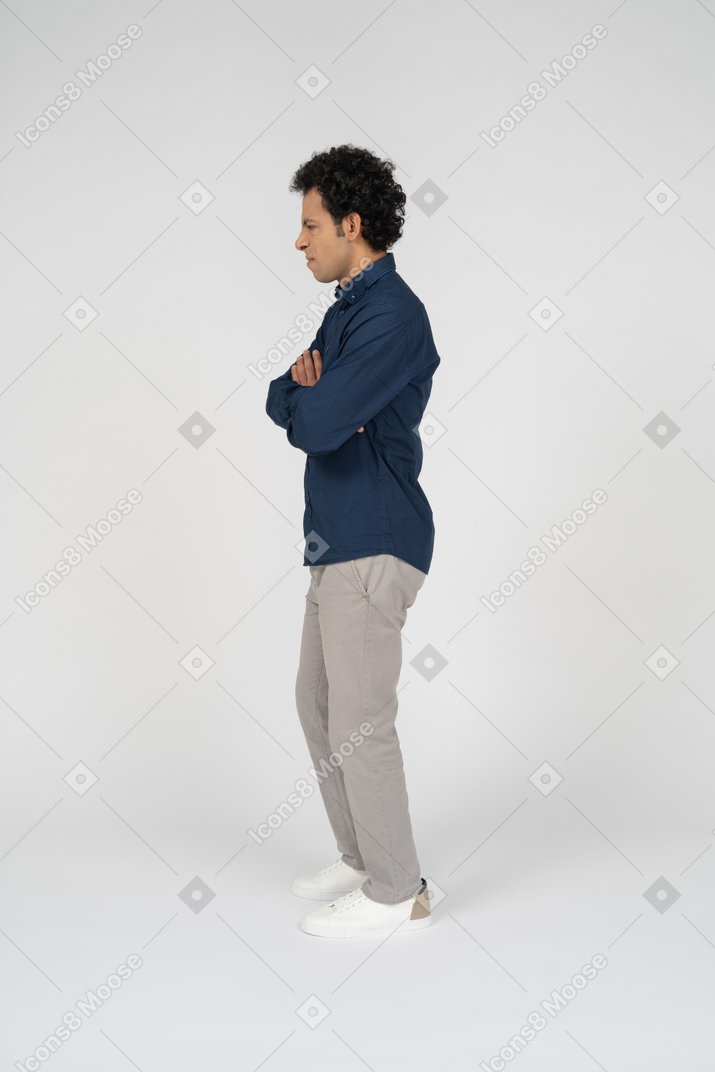 腕を組んで立っているカジュアルな服装の男性の側面図