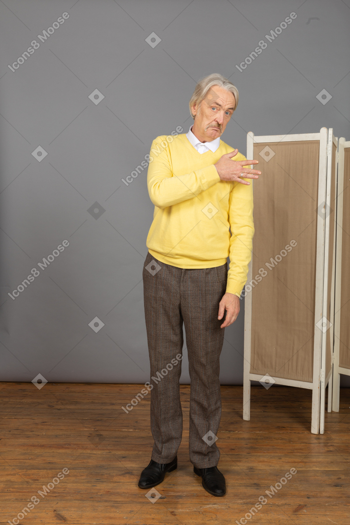 Front view of an old man looking at camera while touching shoulder