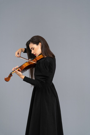 Close-up de uma jovem de vestido preto tocando violino