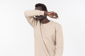 A young black man in a grey sweater standing alone on the white background