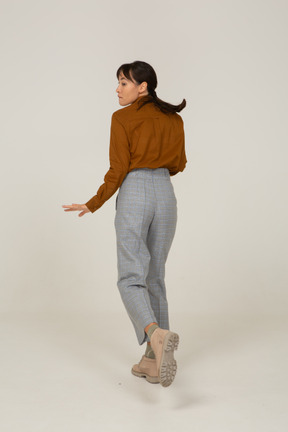 Three-quarter back view of a young asian female in breeches and blouse running away