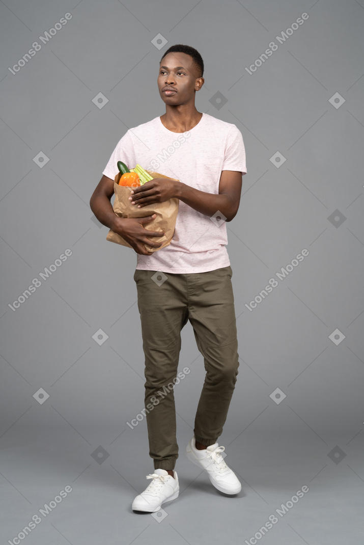 A young man carrying a grocery bag
