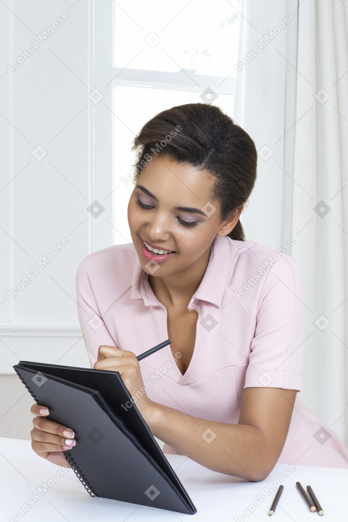 A woman is sitting at a desk and writing in a notebook